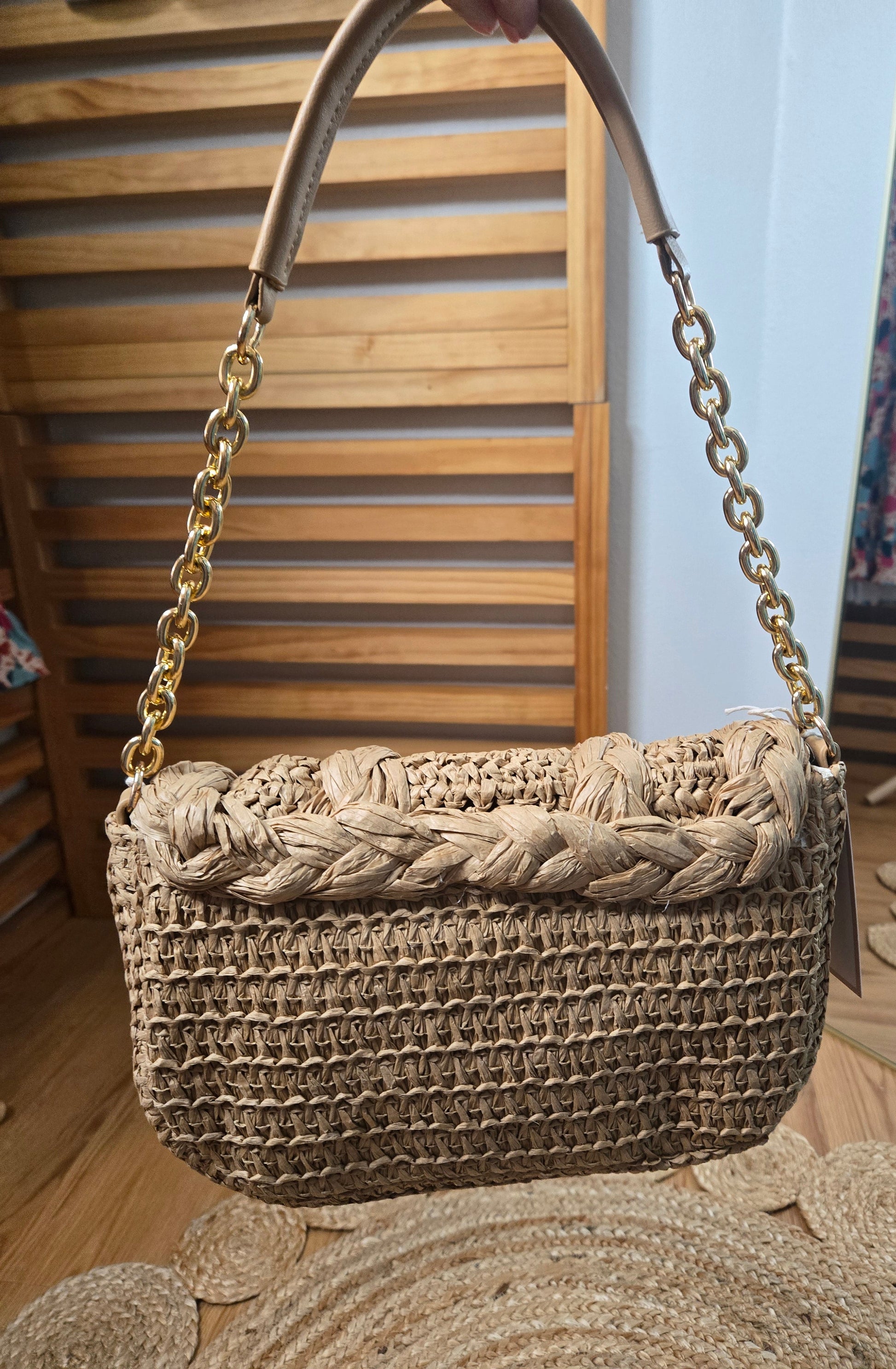 Woven raffia flap shoulder bag with textured natural fibers and structured silhouette