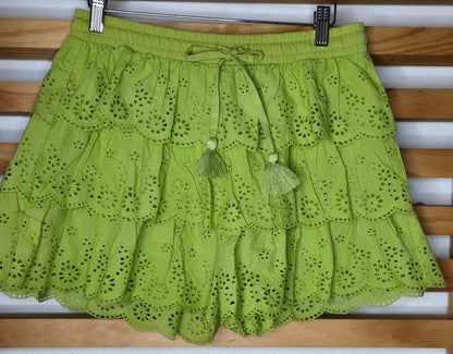 Women's eyelet shorts featuring a tiered ruffle design, elastic waistband, and adjustable tassel drawstring, available in green and white.