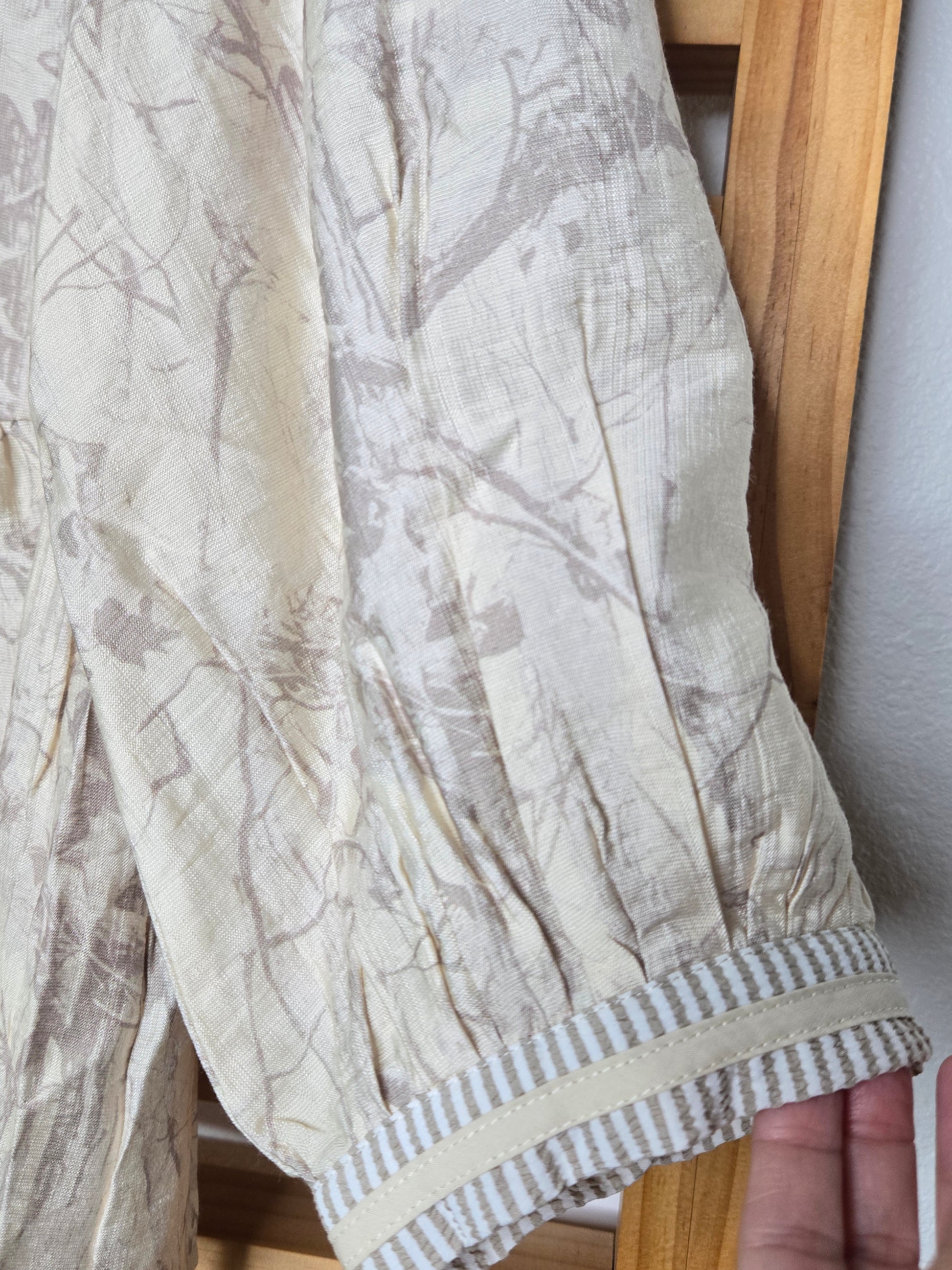 Relaxed peasant-style blouse with subtle camouflage print, tasseled neckline and soft puff sleeves.