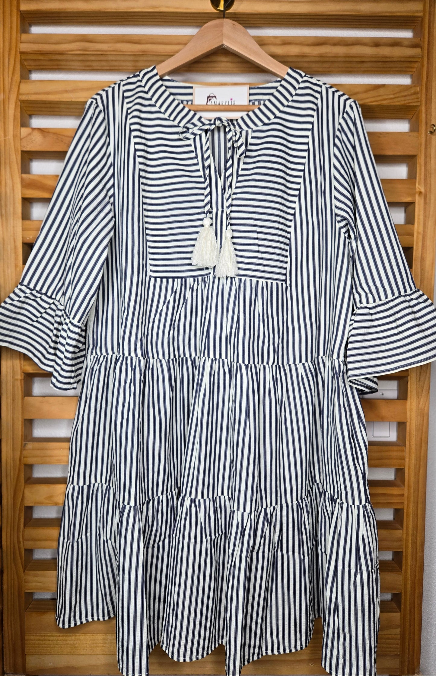 Navy striped cotton babydoll dress with bell sleeves, tassel tie neckline, relaxed fit silhouette, and functional side pockets.