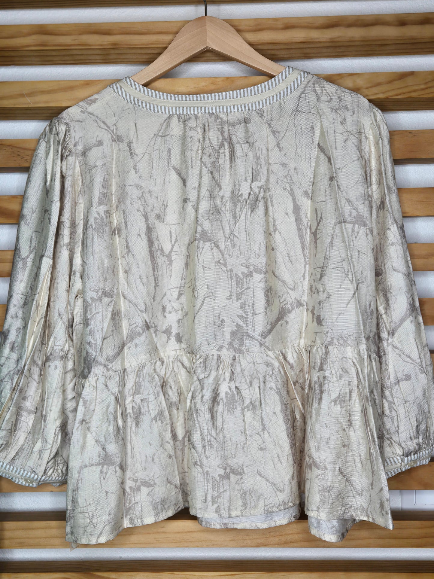 Relaxed peasant-style blouse with subtle camouflage print, tasseled neckline and soft puff sleeves.