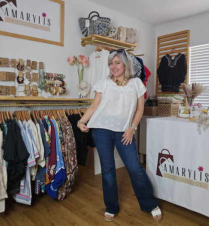 Woman in white shirt and blue jeans walking through a clothing store with 'Amaryllis' branding.