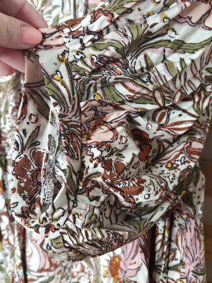 Soft and feminine peasant-style blouse featuring a delicate floral print, 3/4 length puff sleeves, and a tassel-tie neckline. Designed for effortless bohemian