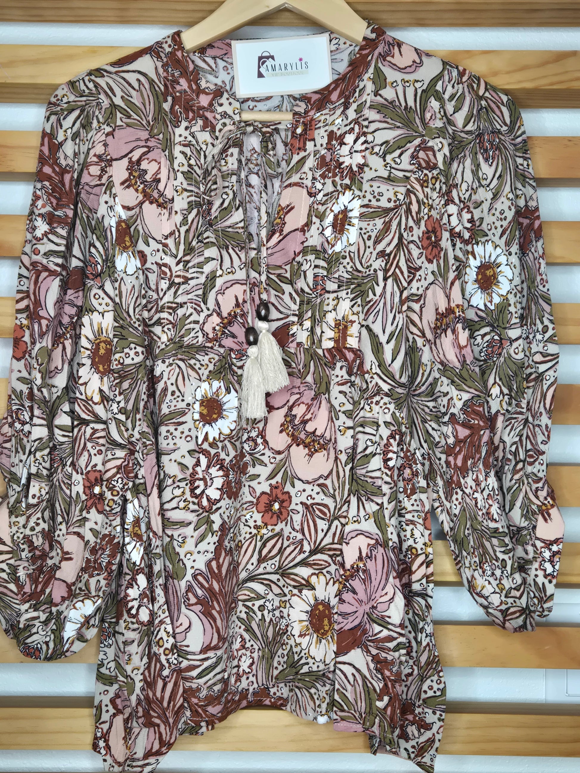 Soft and feminine peasant-style blouse featuring a delicate floral print, 3/4 length puff sleeves, and a tassel-tie neckline. Designed for effortless bohemian
