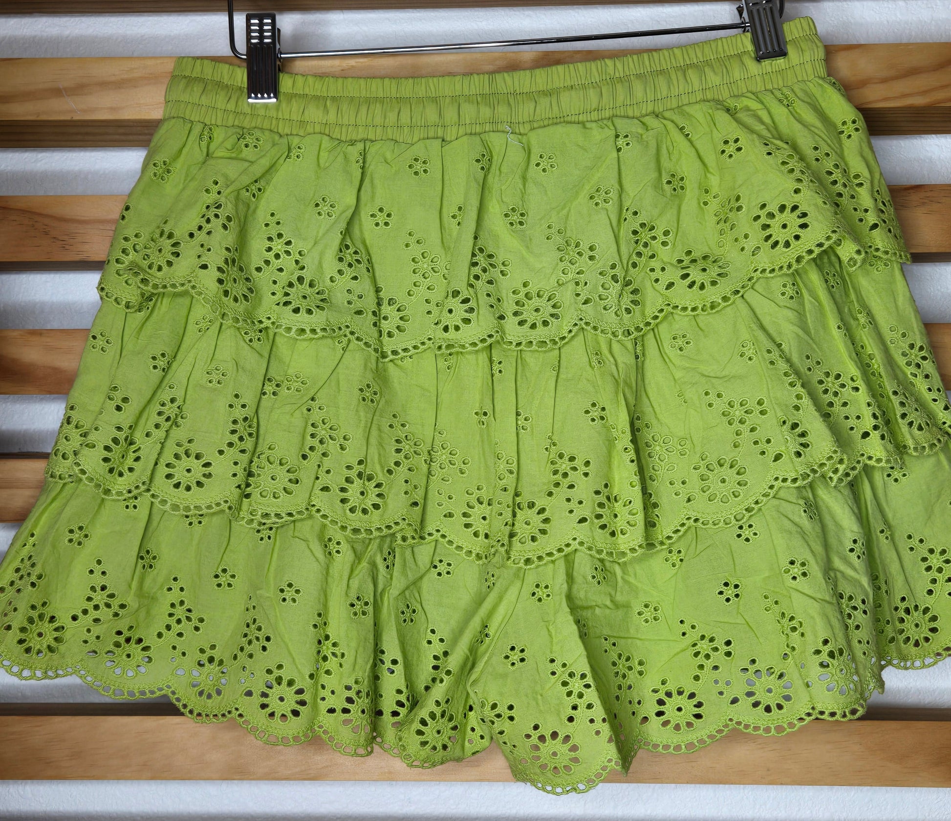 Women's eyelet shorts featuring a tiered ruffle design, elastic waistband, and adjustable tassel drawstring, available in green and white.