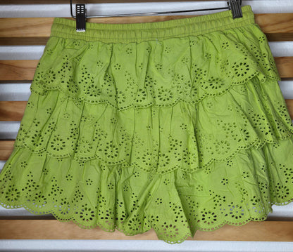 Women's eyelet shorts featuring a tiered ruffle design, elastic waistband, and adjustable tassel drawstring, available in green and white.
