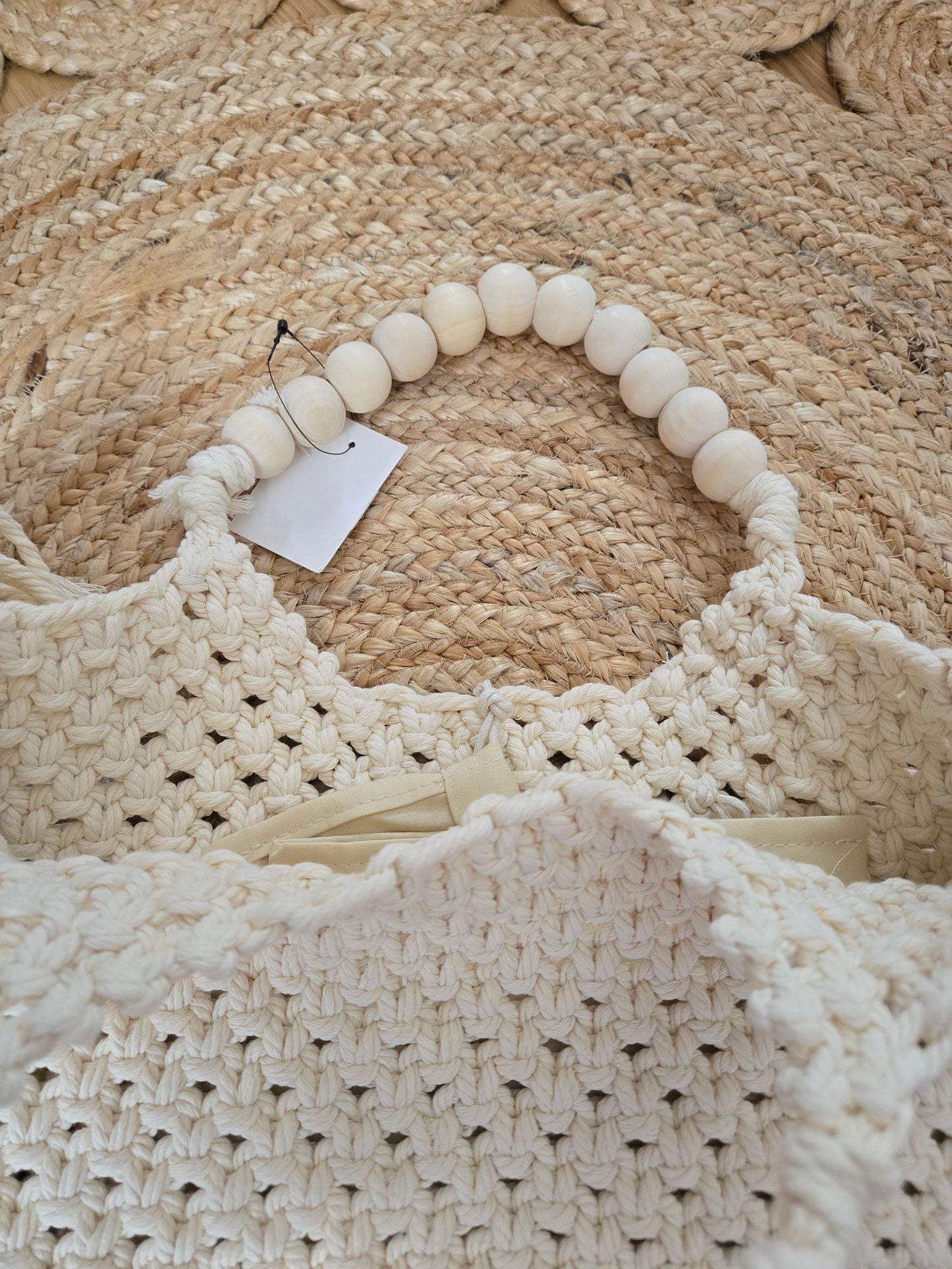 Large woven macrame tote bag with intricate knotted design, long fringe trim, and braided shoulder strap.