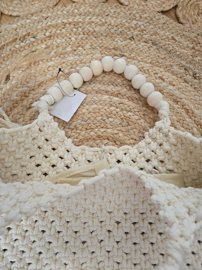Large woven macrame tote bag with intricate knotted design, long fringe trim, and braided shoulder strap.