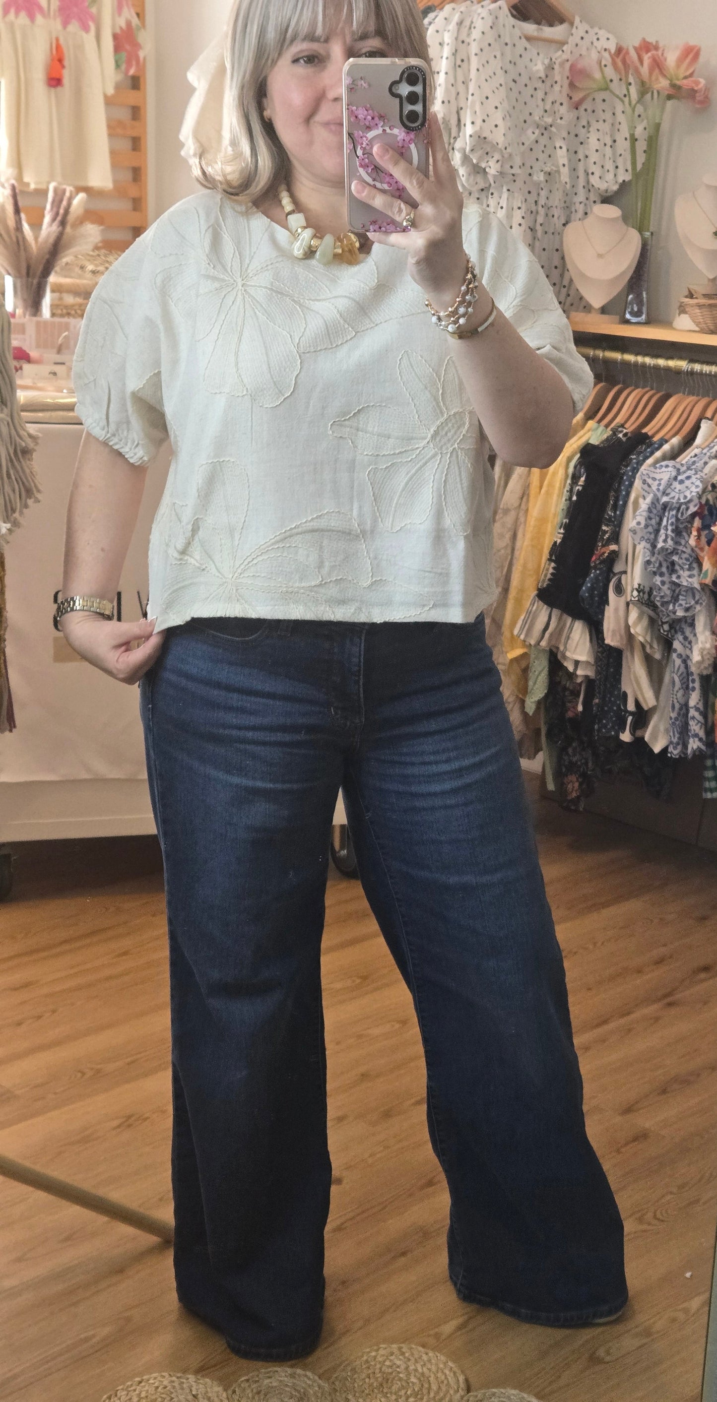 Beige linen-blend top with floral embroidery, featuring short dolman sleeves with elastic cuffs and a soft inner lining
