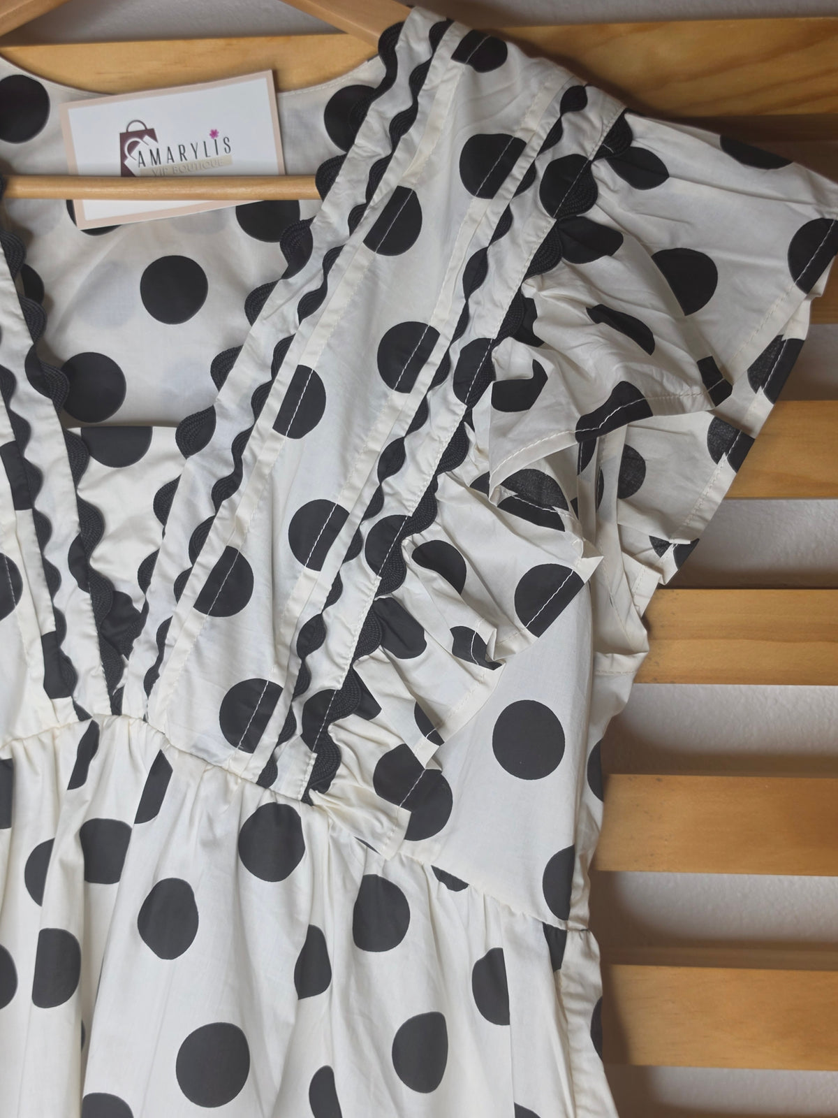 Black and white polka dot babydoll blouse with ruffle details, fitted bust, relaxed lower silhouette, and side zipper.