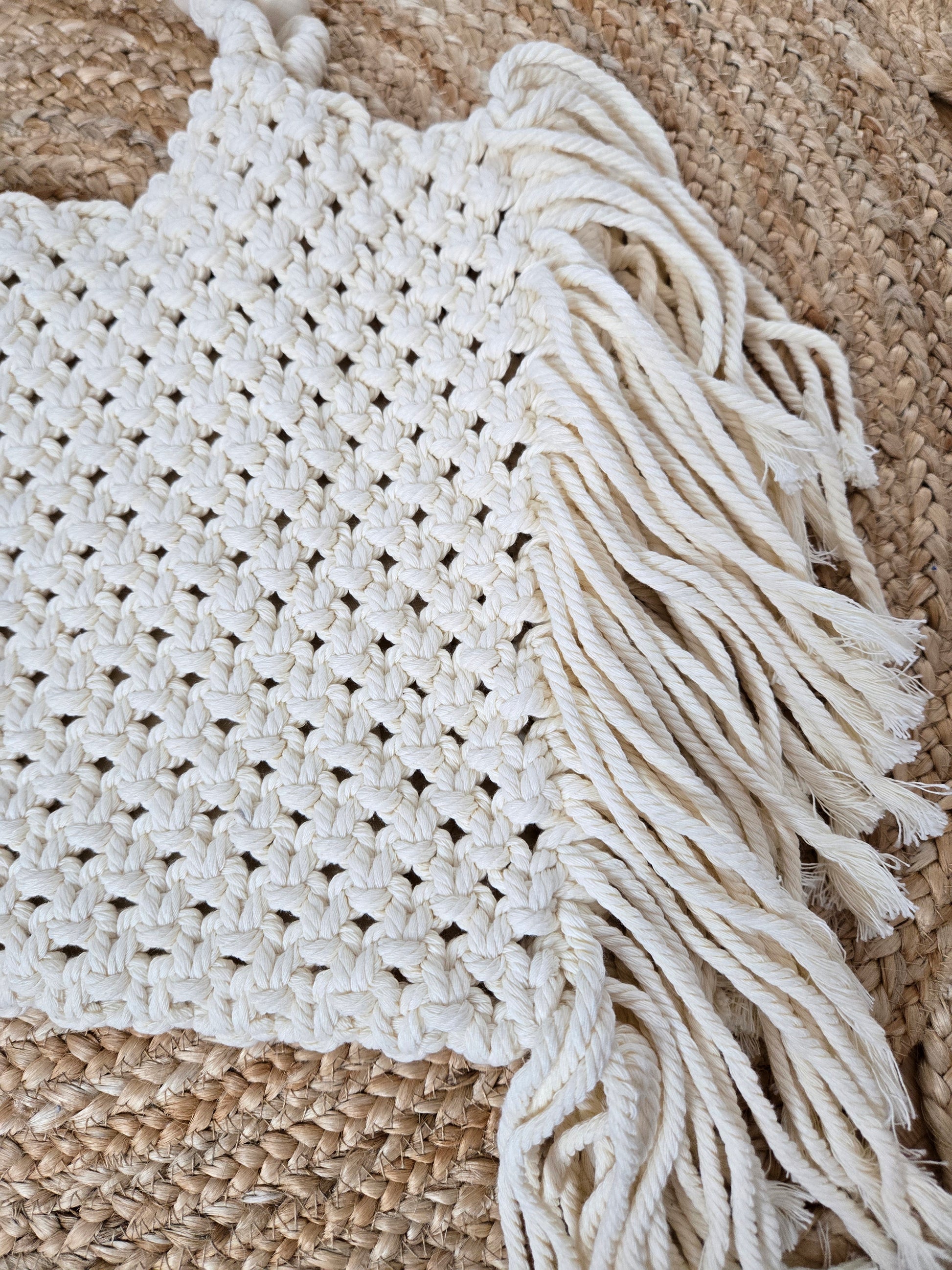 Large woven macrame tote bag with intricate knotted design, long fringe trim, and braided shoulder strap.