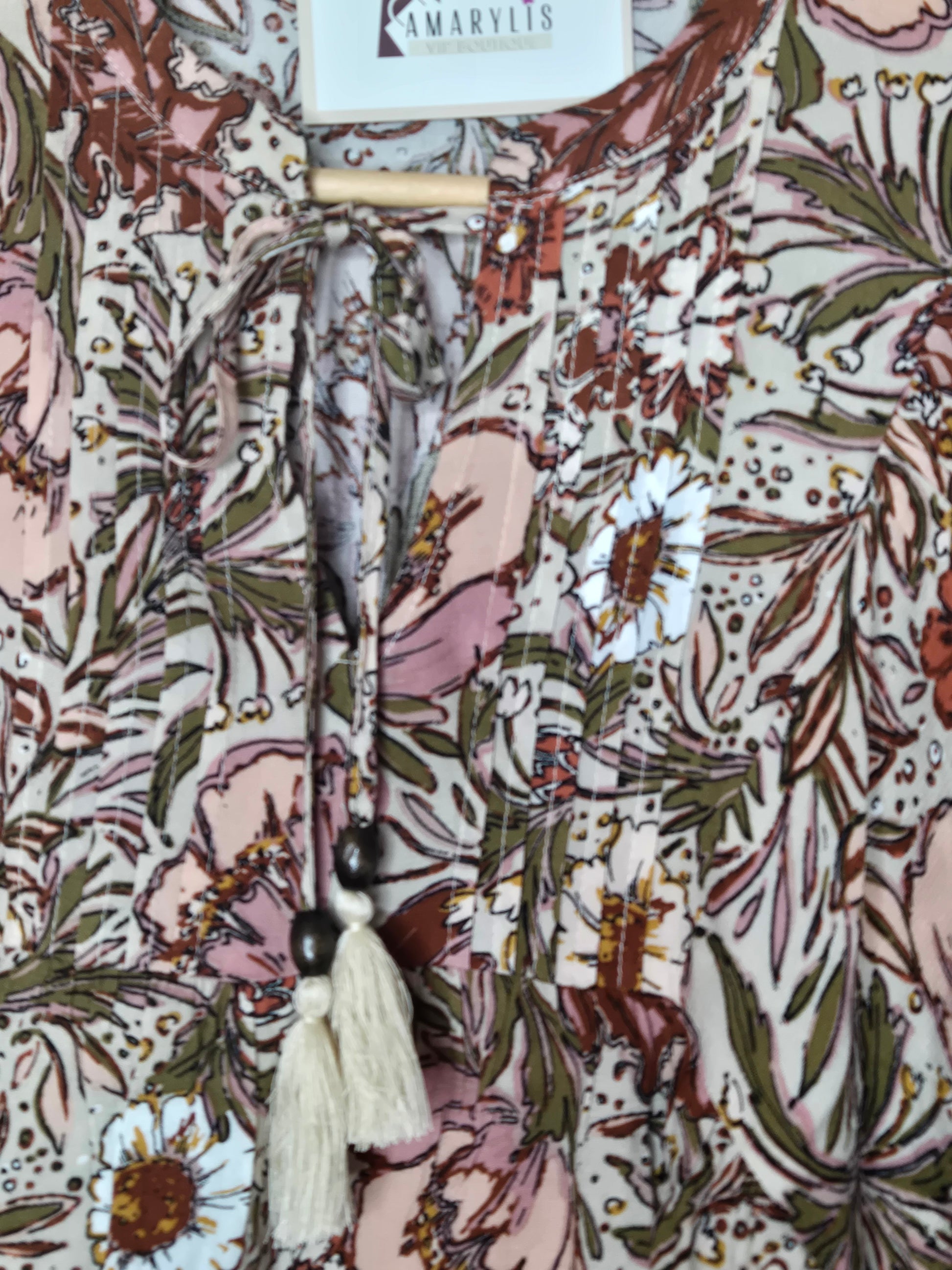 Soft and feminine peasant-style blouse featuring a delicate floral print, 3/4 length puff sleeves, and a tassel-tie neckline. Designed for effortless bohemian