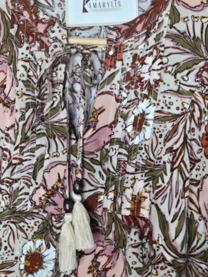 Soft and feminine peasant-style blouse featuring a delicate floral print, 3/4 length puff sleeves, and a tassel-tie neckline. Designed for effortless bohemian