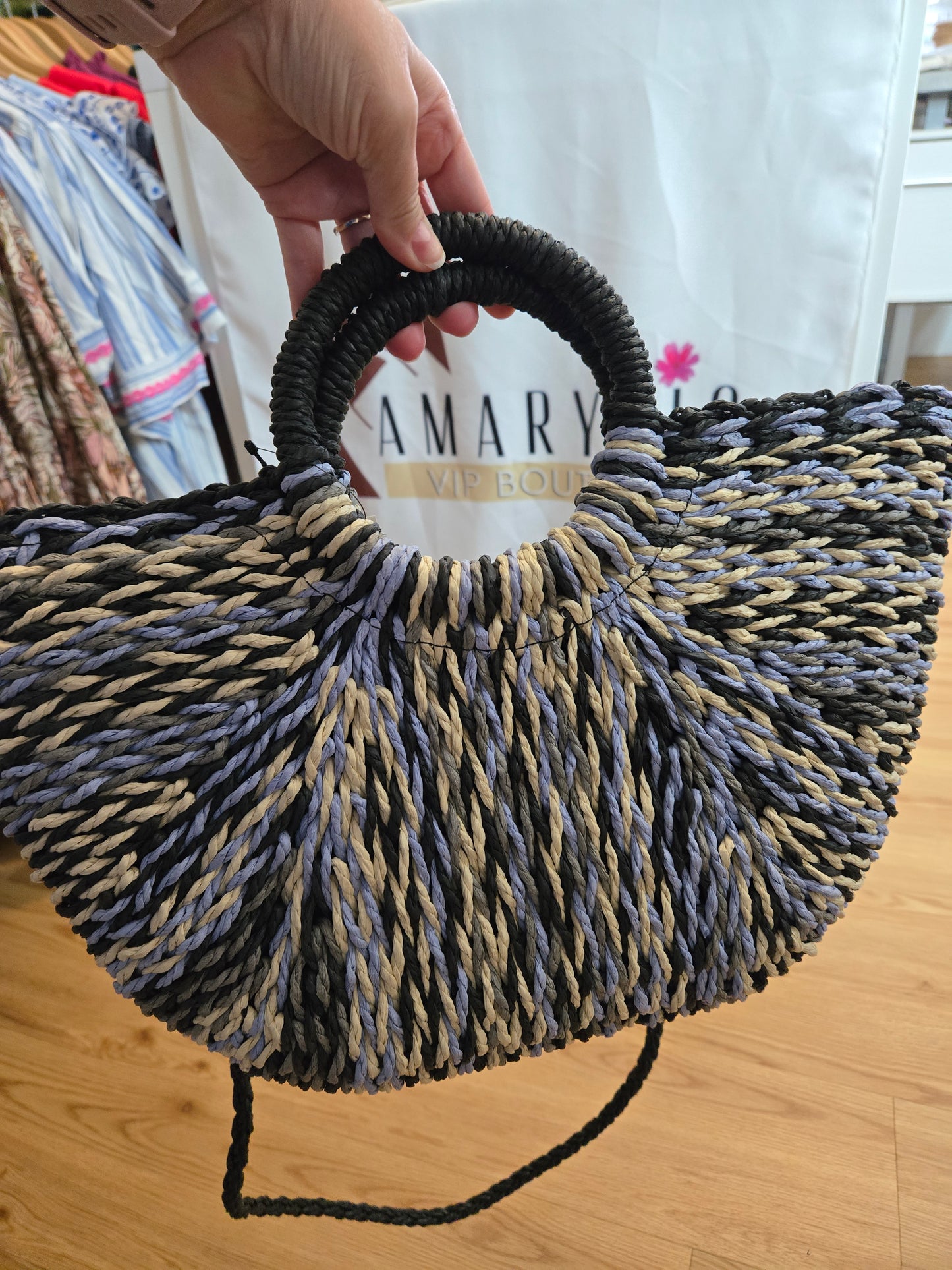 Straw tote bag with a subtle sheen, featuring a multi-tone woven design, distinctive half-moon round handles, a secure zipper closure, and an adjustable strap for crossbody wear. A versatile, timeless piece with a refined yet relaxed style.