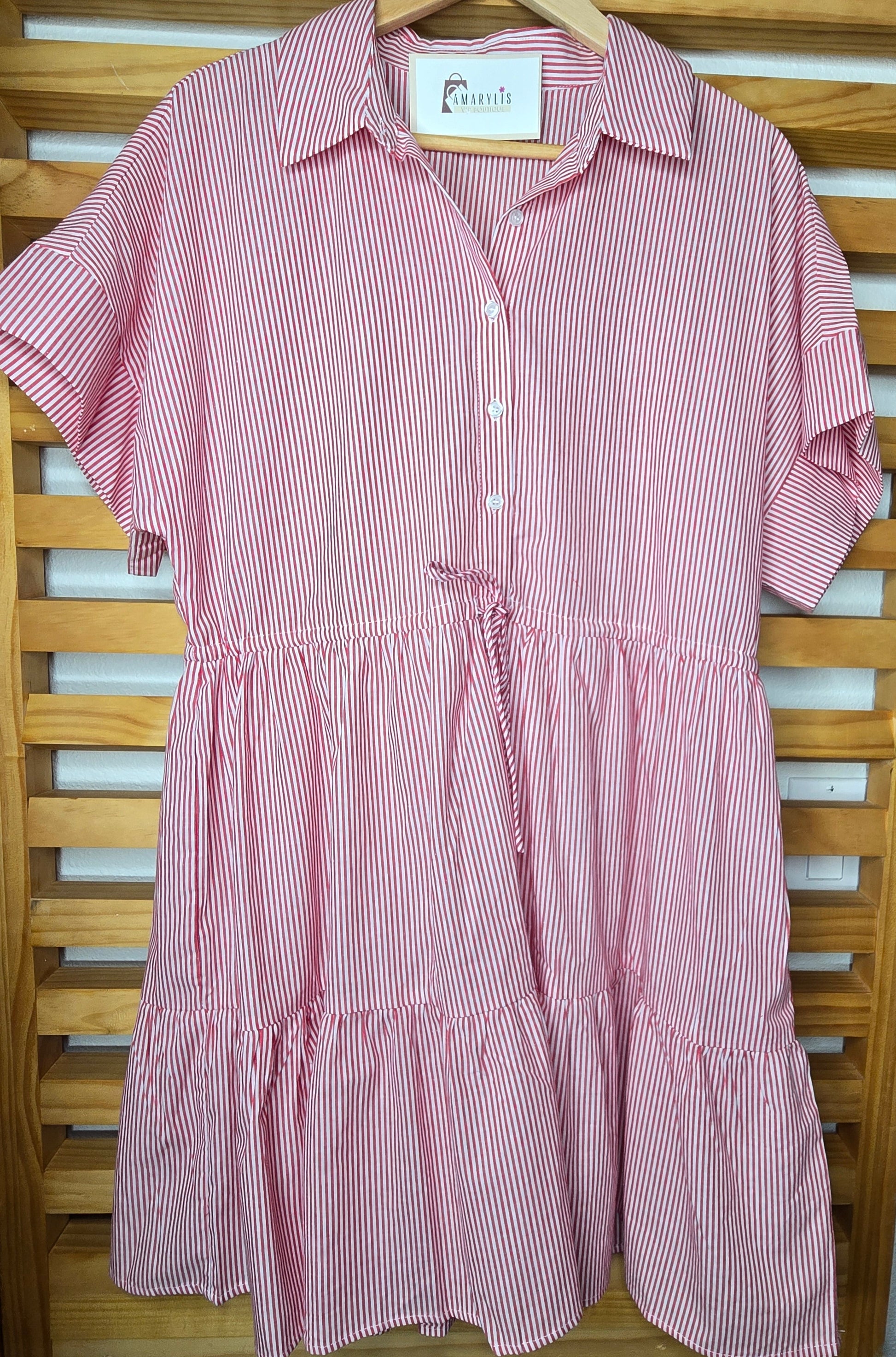 Red striped cotton dress with collared neckline, rolled short sleeves, button front detail, tiered skirt, ruffled hem, and adjustable tie waist.