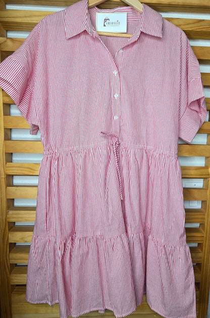 Red striped cotton dress with collared neckline, rolled short sleeves, button front detail, tiered skirt, ruffled hem, and adjustable tie waist.