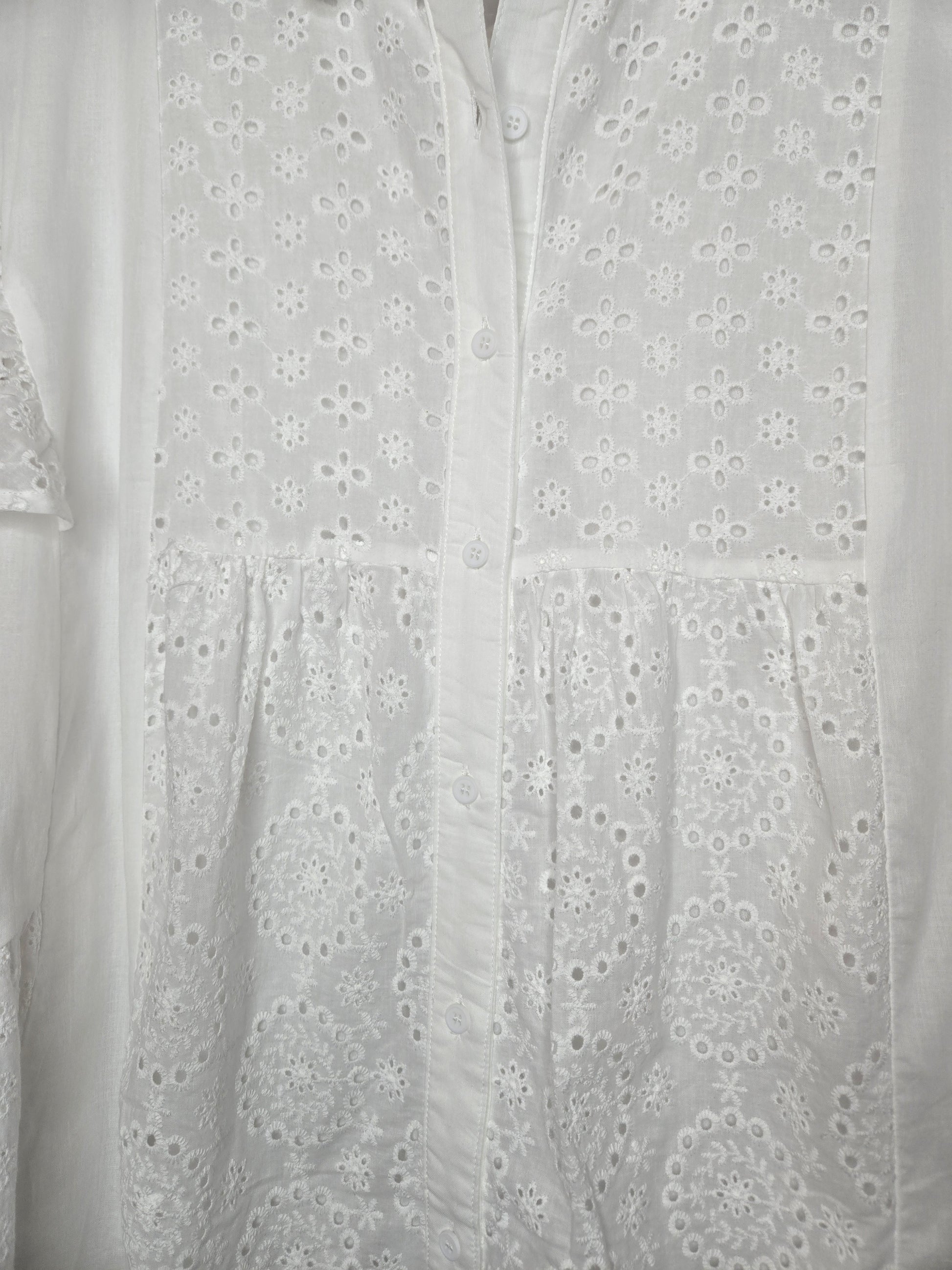 Lightweight shirt dress with eyelet embroidery, button-front closure, short flutter sleeves, and a soft, feminine silhouette.
