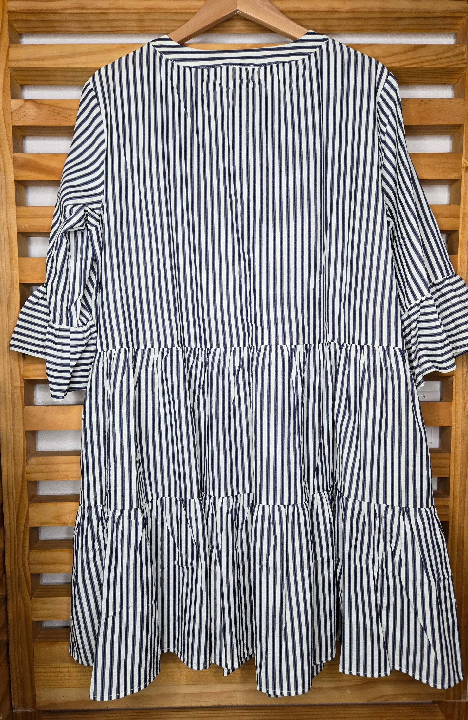 Navy striped cotton babydoll dress with bell sleeves, tassel tie neckline, relaxed fit silhouette, and functional side pockets.