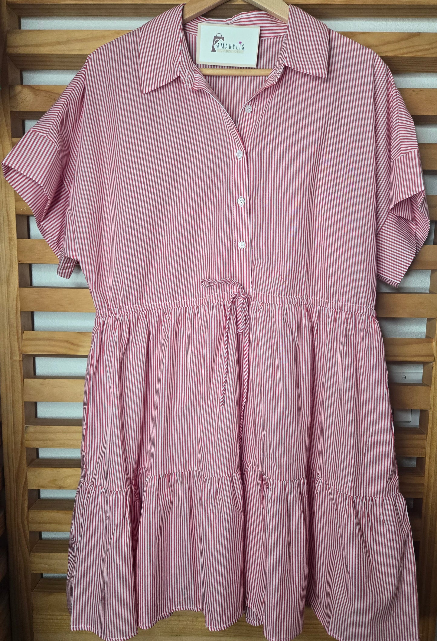 Red striped cotton dress with collared neckline, rolled short sleeves, button front detail, tiered skirt, ruffled hem, and adjustable tie waist.