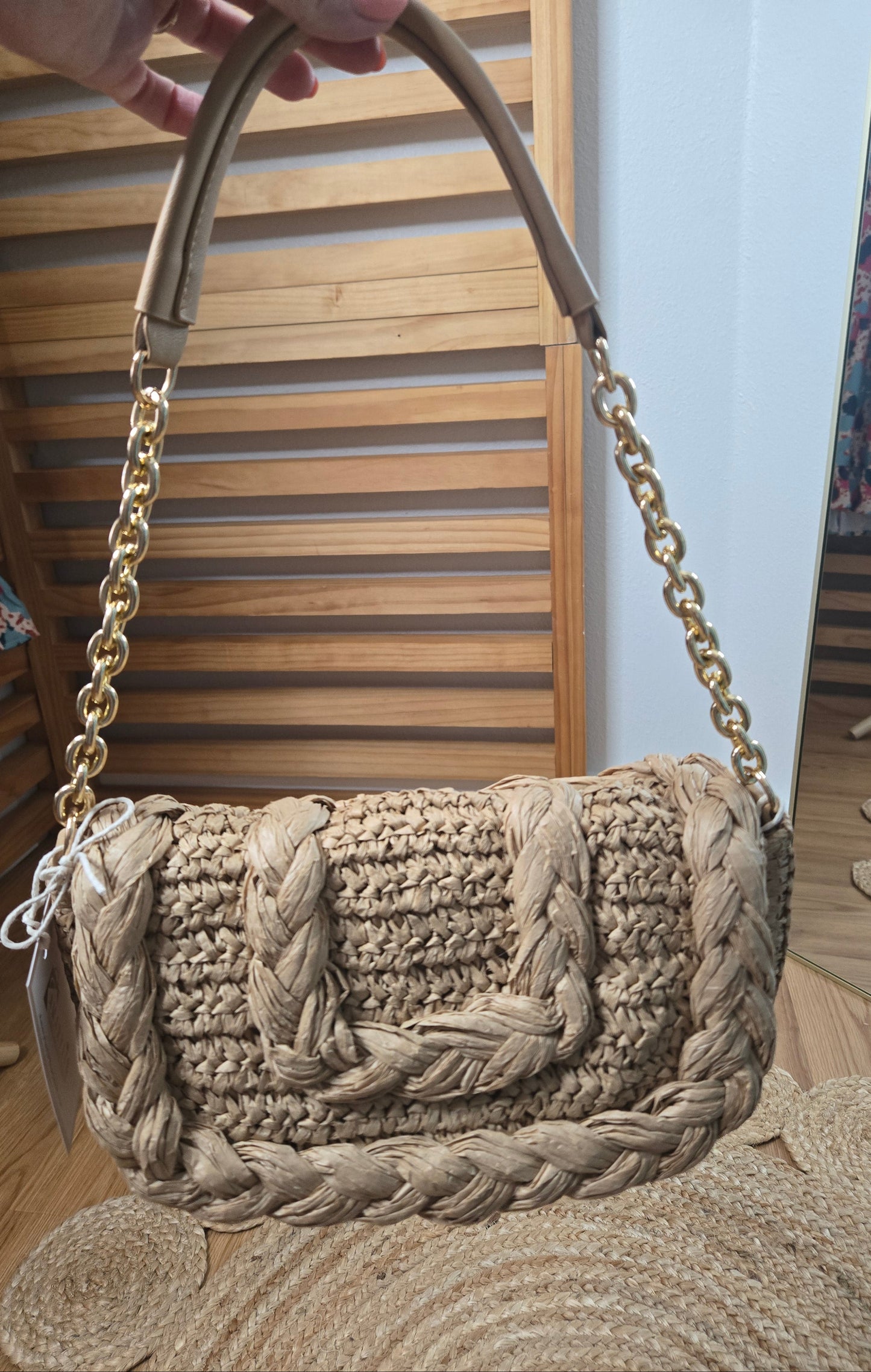 Woven raffia flap shoulder bag with textured natural fibers and structured silhouette