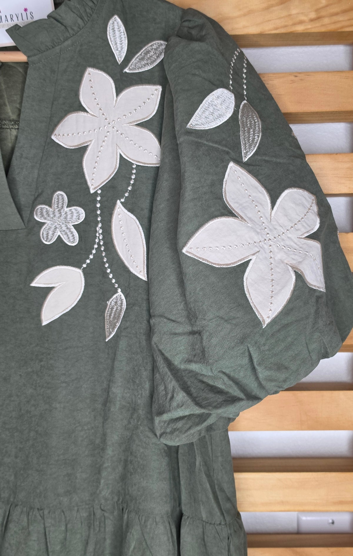Olive boho dress with oversized floral embroidery, puff sleeves, tiered skirt, split neckline, and side pockets.
