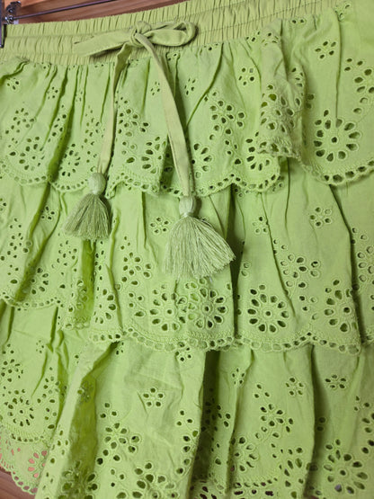 Women's eyelet shorts featuring a tiered ruffle design, elastic waistband, and adjustable tassel drawstring, available in green and white.